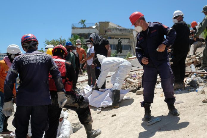 Bomberos y voluntarios rescatan un cuerpo sin vida durante los trabajos de remoción de escombros de los edificios Mision Vivienda OPPE luego del doble terremoto de magnitud 7,2 y 7,5 ocurrido el pasado 24 de Junio, este martes en La Guaira (Venezuela). EFE/ Xaume Olleros
