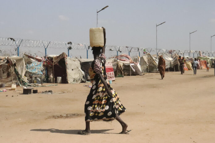 Una mujer transporta sobre su cabeza una garrafa de agua que acaba de rellenar en una fuente en el centro de tránsito de Renk, en el norte de Sudán del Sur. El agua, un bien preciado ante los problemas que causa el estrés bélico en las infraestructuras sanitarias. EFE/Rosa Soto
