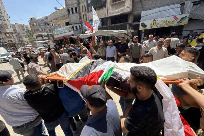 Varios hombres portan el cuerpo de Mohamed Al Wahidi, director de la Oficina de Mujtares y Notables del Comité Egipcio de Ayuda para Gaza, la agencia estatal egipcia encargada del envío de ayuda humanitaria al enclave, cubierto de una bandera egipcia, desde una ambulancia hasta su casa del barrio de Al Sabra, y de allí al cementerio, durante el funeral celebrado este miércoles en Ciudad de Gaza. El Ejército israelí mató a Al Wahidi en un ataque perpetrado en el barrio de Al Sabra de Ciudad de Gaza en el que también murieron dos niños de 8 y 10 años y un hombre de 30, según informó el hospital gazatí Al Shifa. El ataque coincidió con el partido Egipto - Argentina del Mundial de fútbol, que miles de gazatíes siguiendo en apoyo al país vecino. EFE/ Ahmad Awad
