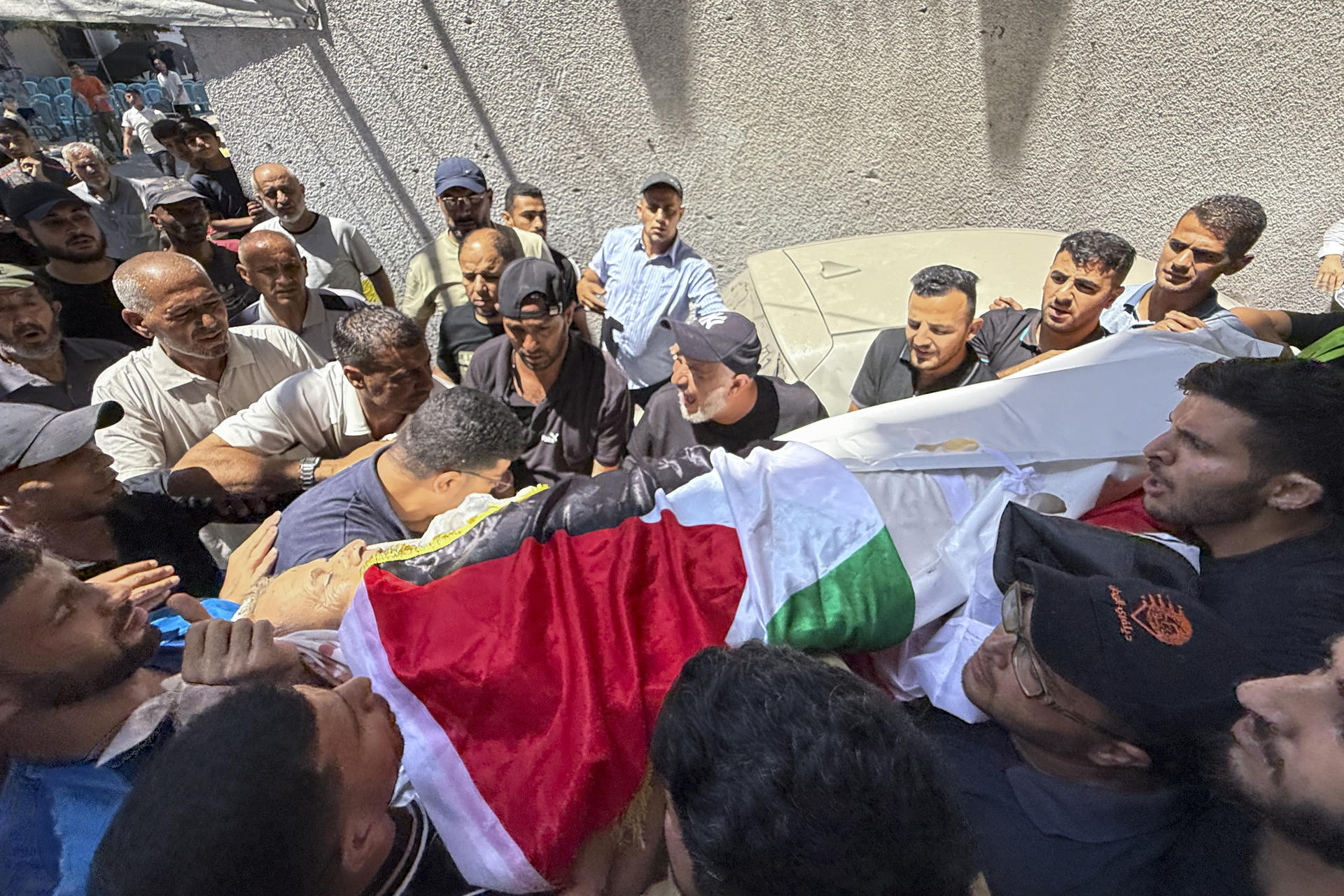 Varios hombres portan el cuerpo de Mohamed Al Wahidi, director de la Oficina de Mujtares y Notables del Comité Egipcio de Ayuda para Gaza, la agencia estatal egipcia encargada del envío de ayuda humanitaria al enclave, cubierto de una bandera egipcia, desde una ambulancia hasta su casa del barrio de Al Sabra, y de allí al cementerio, durante el funeral celebrado este miércoles en Ciudad de Gaza. El Ejército israelí mató a Al Wahidi en un ataque perpetrado en el barrio de Al Sabra de Ciudad de Gaza en el que también murieron dos niños de 8 y 10 años y un hombre de 30, según informó el hospital gazatí Al Shifa. El ataque coincidió con el partido Egipto - Argentina del Mundial de fútbol, que miles de gazatíes siguiendo en apoyo al país vecino. EFE/ Ahmad Awad