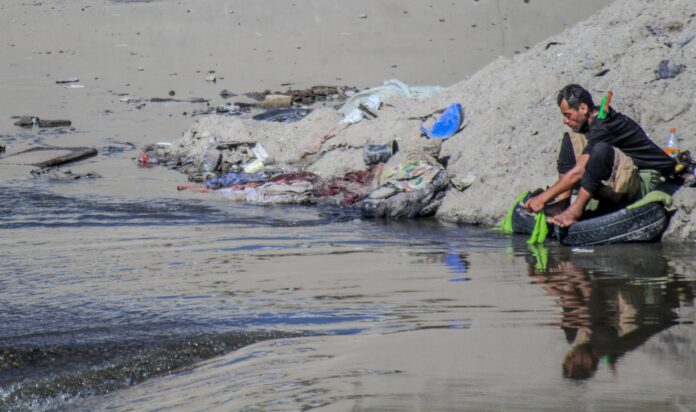 Fotografía de archivo de un migrante en condición de indigencia que lava su ropa en los charcos del río Bravo, que se mantiene sin afluente, en la ciudad de Tijuana (México). EFE/ Joebeth Terriquez

