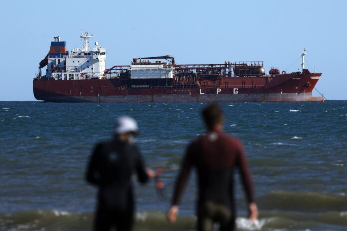 Fotografía de archivo de dos surferos frente a un barco petrolero en Fos-sur-Mer, en el sur de Francia. EFE/EPA/GUILLAUME HORCAJUELO
