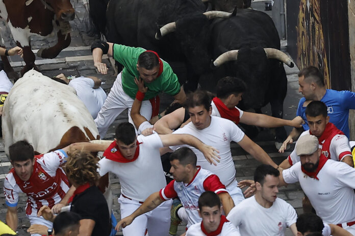 Los mozos corren entre los toros bravos de la ganadería Victoriano del Río durante el tercer encierro de los Sanfermines, este jueves en Pamplona. EFE/Villar López
