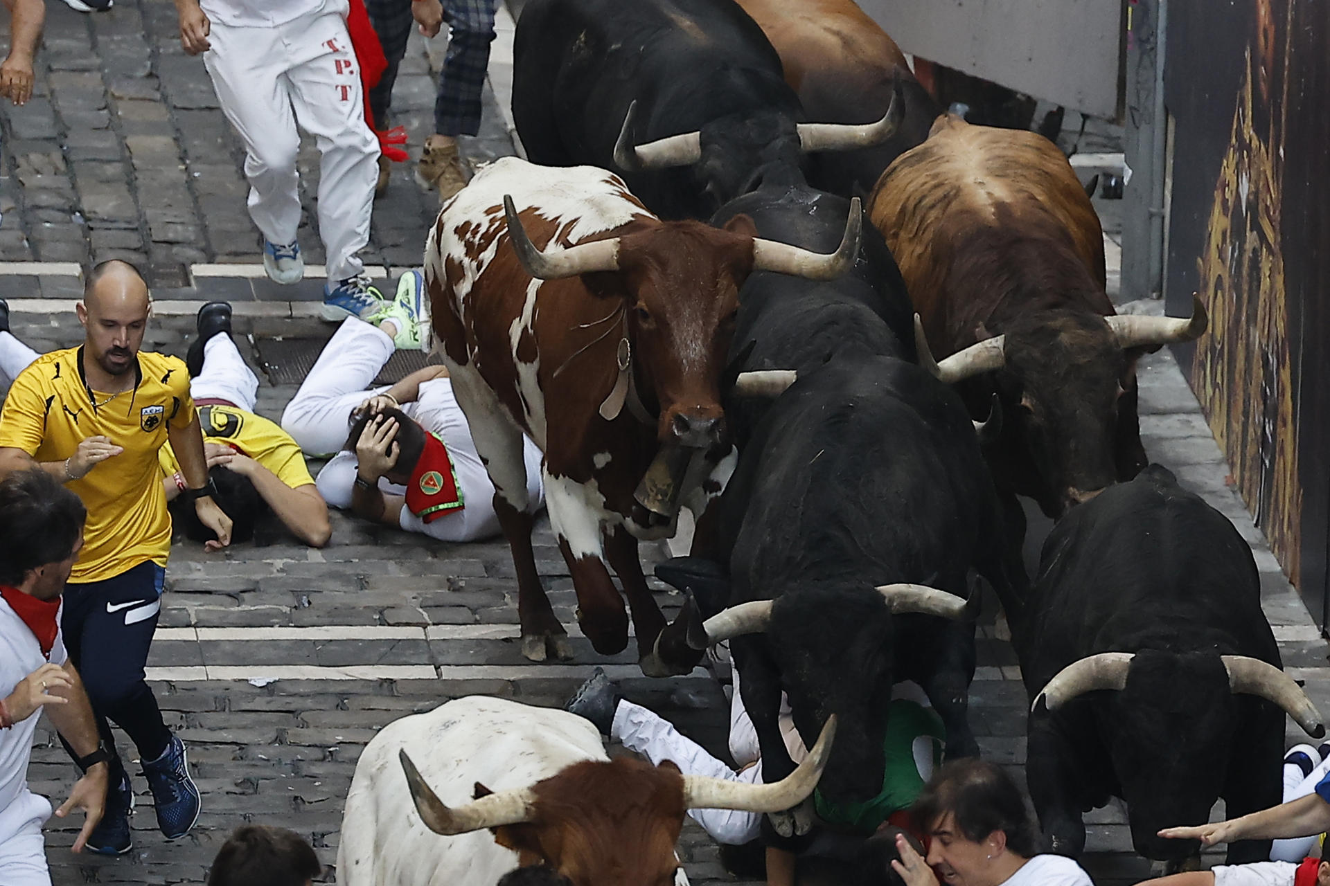 Varios corredores caen al paso de los toros durante el tercer encierro de los Sanfermines, este jueves en Pamplona. EFE/Villar López