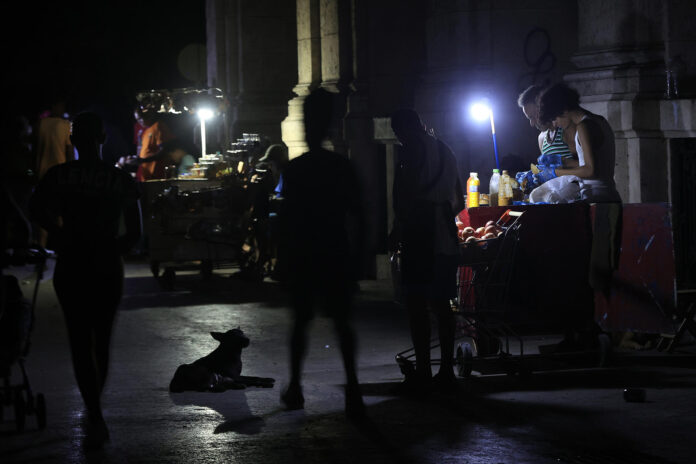 AME8405. LA HABANA (CUBA), 08/07/2026.- Personas venden productos en una calle durante un apagón este martes, en La Habana (Cuba). Cuba restableció este miércoles el Sistema Electroenergético Nacional (SEN), tras la caída general que sufrió el lunes, sin embargo, los prolongados apagones afectarán al 66% del país esta jornada durante el horario “pico”, el de mayor demanda (tarde-noche). EFE/ Ernesto Mastrascusa
