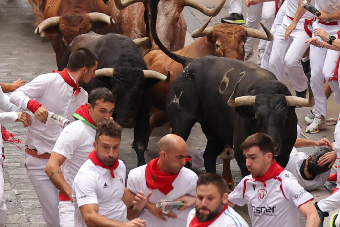 Varios mozos son embestidos por uno de los toro bravos en el cuarto encierro de los Sanfermines 2026 este viernes en Pamplona. EFE/ Jesús Diges
