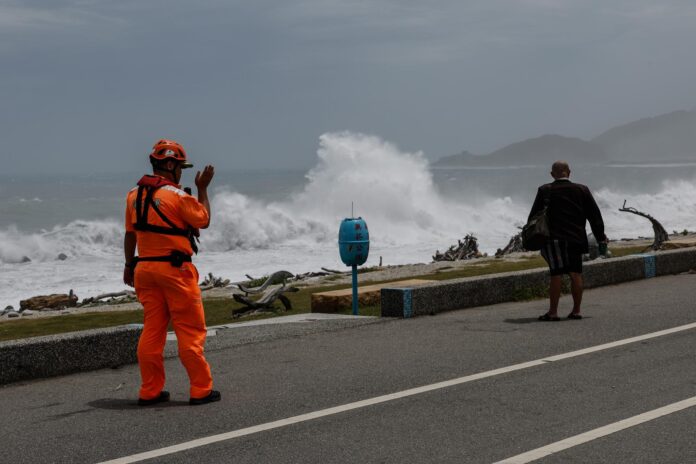 HUALIEN (Taiwán) - Un guardia costero de Taiwán advierte a un residente que contempla las grandes olas provocadas por el tifón Bavi. EFE/EPA/RITCHIE B. TONGO
