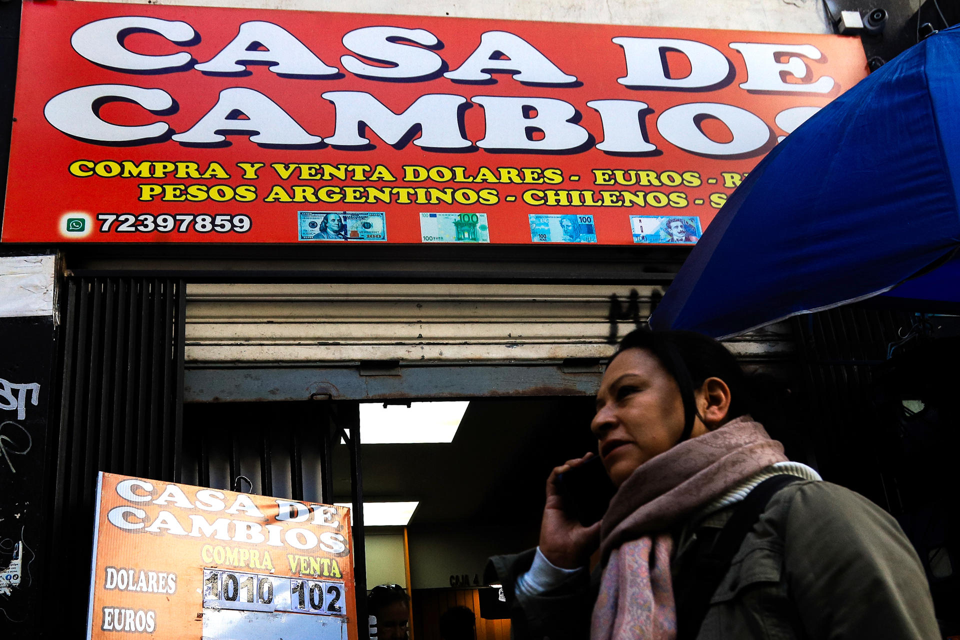 Una persona camina frente a una casa de cambio de divisas este jueves, en La Paz (Bolivia). La aplicación de un tipo de cambio flexible en Bolivia tras 15 años de un esquema fijo no resolverá por sí misma la falta de dólares que sufre desde 2023 el país advirtieron analistas. EFE/ Gabriel Márquez