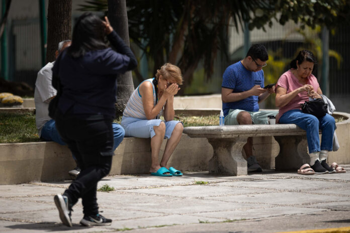 Personas esperan en una calle, luego de un temblor de magnitud 3,9, en Caracas (Venezuela). EFE/ Ronald Peña R
