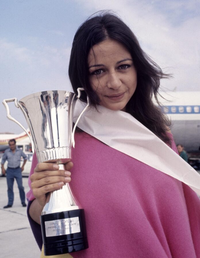 La actriz Emma Cohen muestra la copa que le acredita como Lady Europa 1971 a su llegada al aeropuerto de Barajas. EFE Archivo
