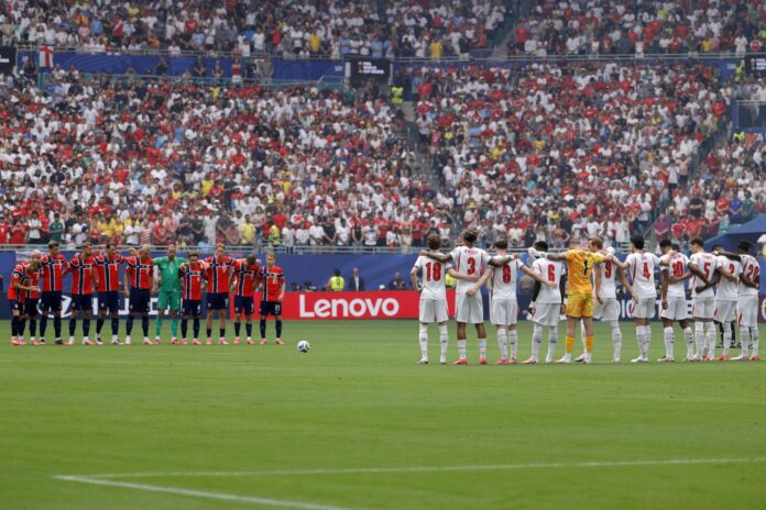 Jugadores de Noruega (izquierda) e Inglaterra (derecha) guardan un minuto de silencio por el fallecido jugador Jayden Adams, de Sudáfrica. EFE/EPA/SHAWN THEW
