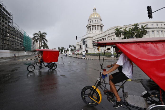 Un par de bicitaxis fue captado este 11 de julio frente al Capitolio de La Habana (Cuba), mientras el país padece el segundo apagón eléctrico nacional de esta semana y el cuarto del año. EFE/Ernesto Mastrascusa
