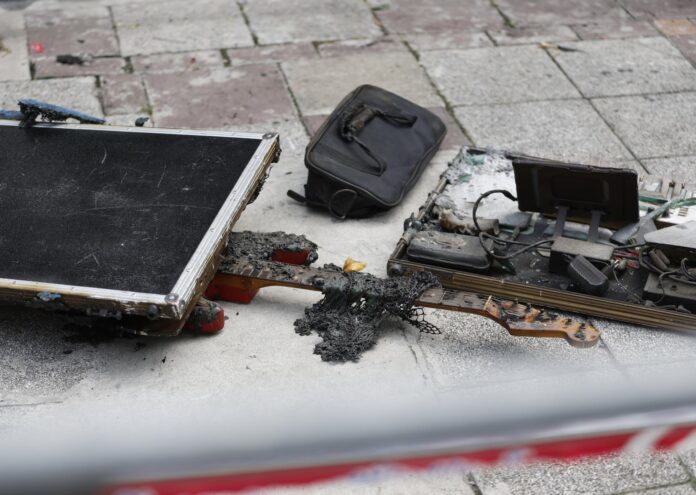 BANGKOK (Tailandia), 13/07/2026.- Una guitarra carbonizada yace entre los escombros mientras un agente de la policía forense tailandesa examina los cristales rotos en el lugar del incendio mortal ocurrido en un bar de Bangkok. EFE/EPA/RUNGROJ YONGRIT

