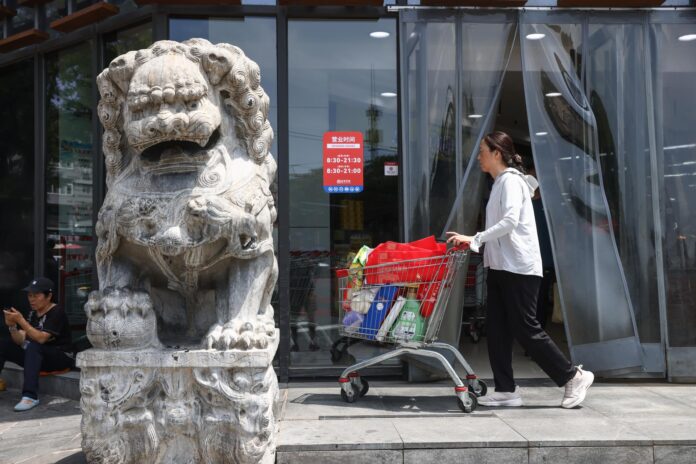 PEKÍN (China), 14/07/2026.- Una mujer camina con un carrito cerca de un supermercado en Pekín. EFE/EPA/WU HAO
