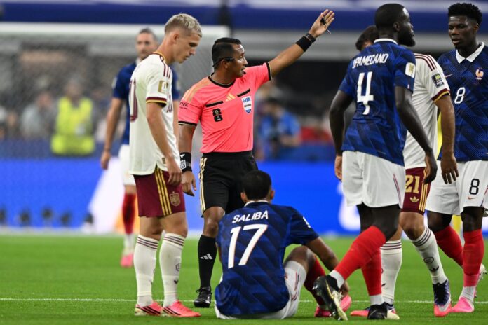 El árbitro Ivan Barton (C) junto a William Saliba, en el partido de semifinales del Mundial de la FIFA 2026 entre Francia y España en el estadio AT&T en Arlington (Estados Unidos).  EFE/EPA/ALBERT PENA
