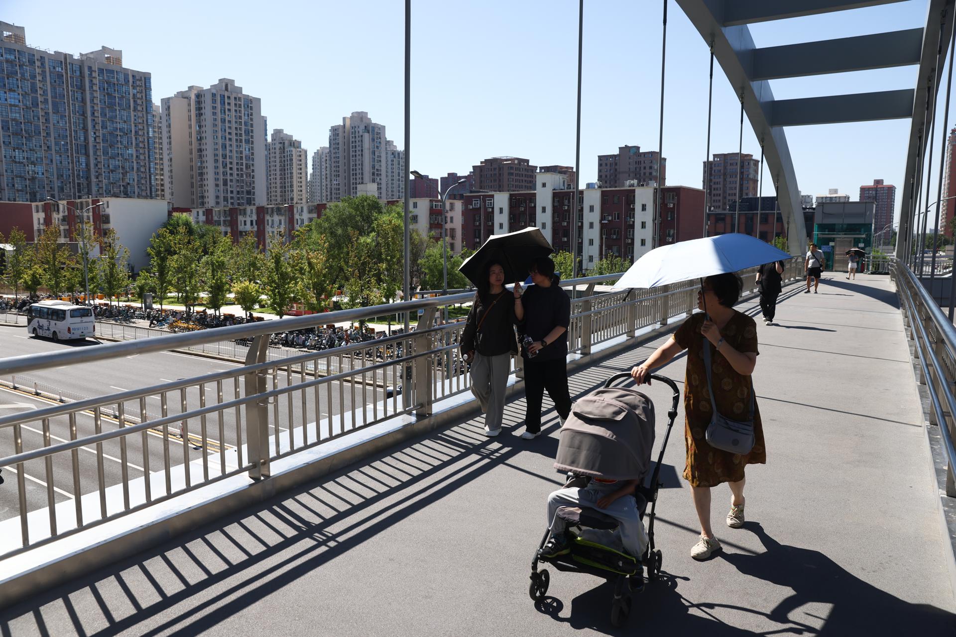 BEIJING (China), 15/07/2026.- Varias personas caminan por un paso elevado en el distrito central de negocios (CBD) de Pekín. 
EFE/EPA/WU HAO
