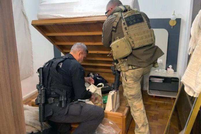 Captura de video cedido por el Gobierno de Río de Janeiro que muestra a autoridades brasileñas durante la detención este miércoles de diez personas en una operación contra una red acusada de lavar dinero procedente del narcotráfico para tres de las principales organizaciones criminales del país y que tendría vínculos con un integrante del grupo terrorista Al-Qaeda, informaron fuentes oficiales. EFE/ Gobierno de Río de Janeiro
