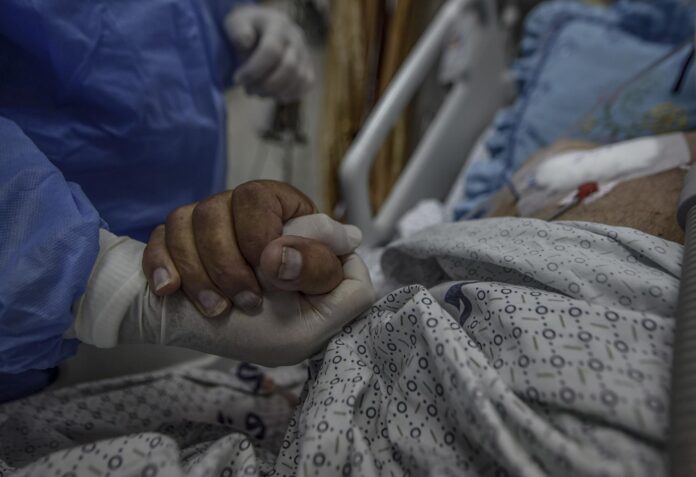 Imagen de archivo de un sanitario que agarra la mano de un paciente del hospital Al-Nasser, al sur de la Franja de Gaza. EFE/Mohammed Saber
