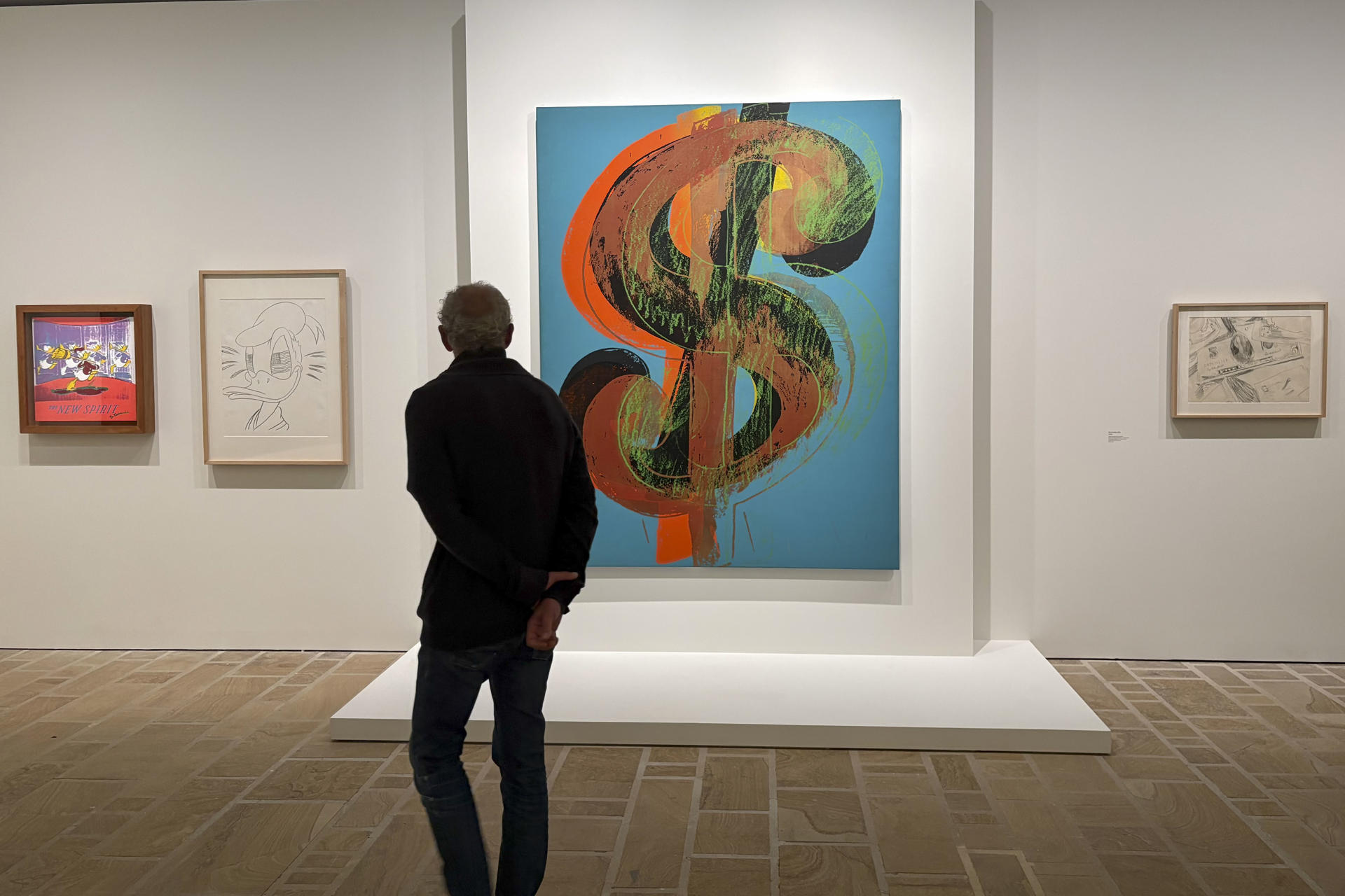 Un visitante observa el símbolo del dólar en una obra de Warhol. EFE/ Pol Lloberas
