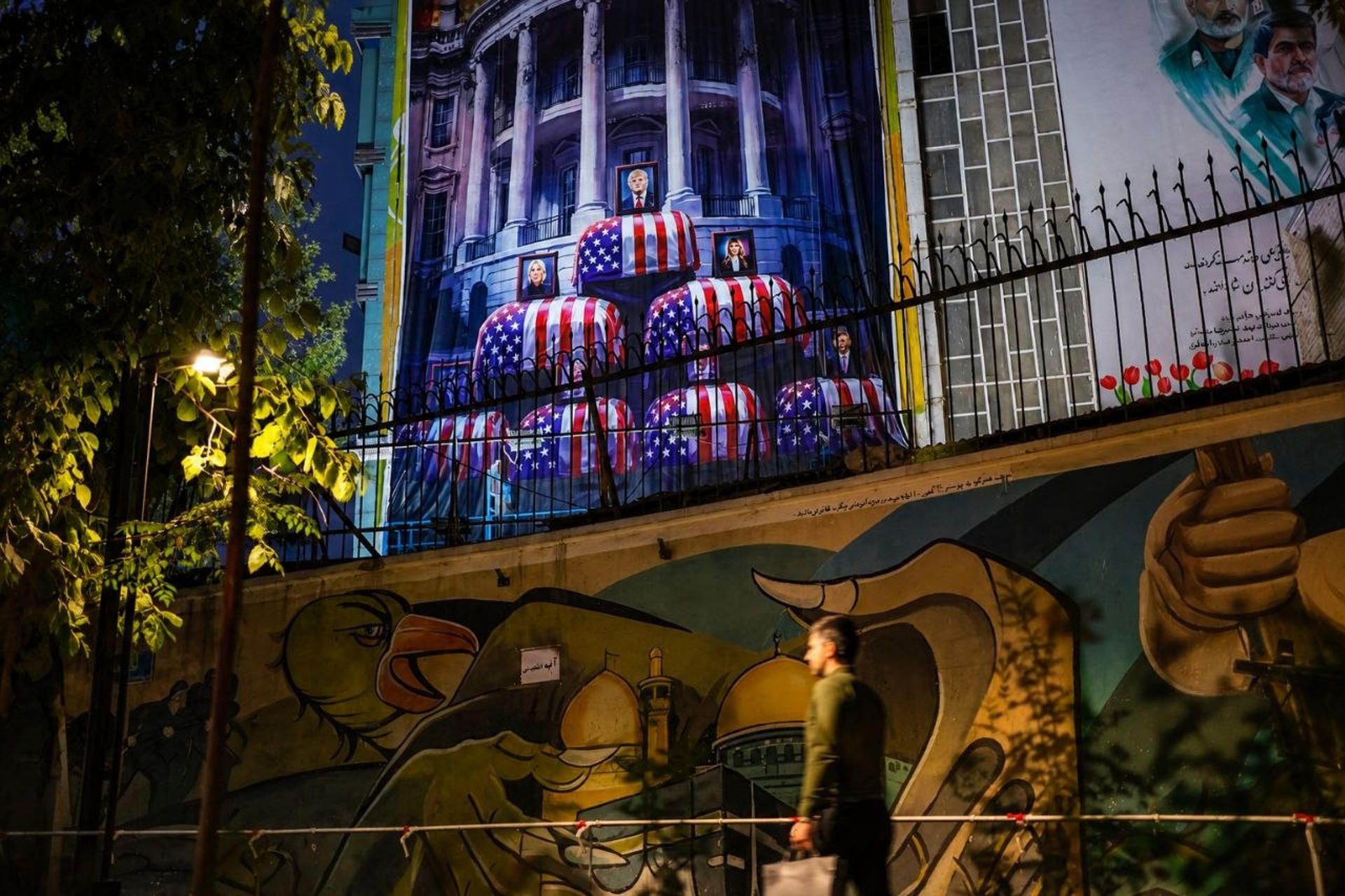 Un hombre a unos metros de un enorme mural que muestra al presidente estadounidense Donald Trump en un ataúd, acompañada de una frase en persa que dice: "mataremos a Trump", en la plaza Engelab, en el centro de Teherán, Irán este viernes.
Seis noches consecutivas de ataques estadounidenses contra el sur de Irán han instalado de nuevo el miedo y la incertidumbre en las calles de Teherán, donde una parte de la población teme que la escalada termine llevando de nuevo la guerra hasta la capital, mientras otros la afrontan con un sentimiento de desafío y llamadas a la venganza. EFE/ Aydin Shayegan
