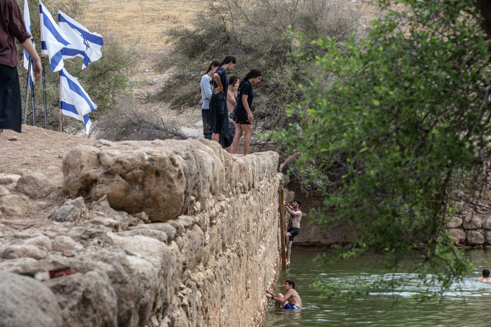 FASAYIL (CISJORDANIA), 17//07/2026.- Colonos y soldados israelíes se bañan en una poza que asocian al Rey Herodes cerca del asentamiento ilegal de Petzael, situado en territorio palestino -en el Valle del Jordán en Cisjordania ocupada- que se ha convertido en una atracción turística para colonos, soldados israelíes y judíos religiosos, después de que los primeros desviaran agua hacia este sitio arqueológico, aún sin excavar, y sin permiso de las autoridades. "Ahora necesitamos que este lugar se llene de una fuerte presencia israelí para viajar, disfrutar y proteger nuestro país", continúa el bloguero Elhanan Benistyel sobre este enclave bautizado por los colonos como 'Poza de Herodes'. EFE/Patricia Martinez