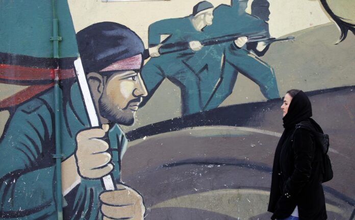 FOTO ARCHIVO. Una mujer  pasa junto a un mural de soldados de la Guardia Revolucionaria iraní en una calle de Teherán, Irán.  EFE/EPA/ABEDIN TAHERKENAREH
