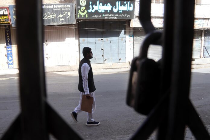 Un hombre camina junto a tiendas cerradas durante una huelga general en Quetta, Pakistán, este viernes. EFE/EPA/FAYYAZ AHMAD
