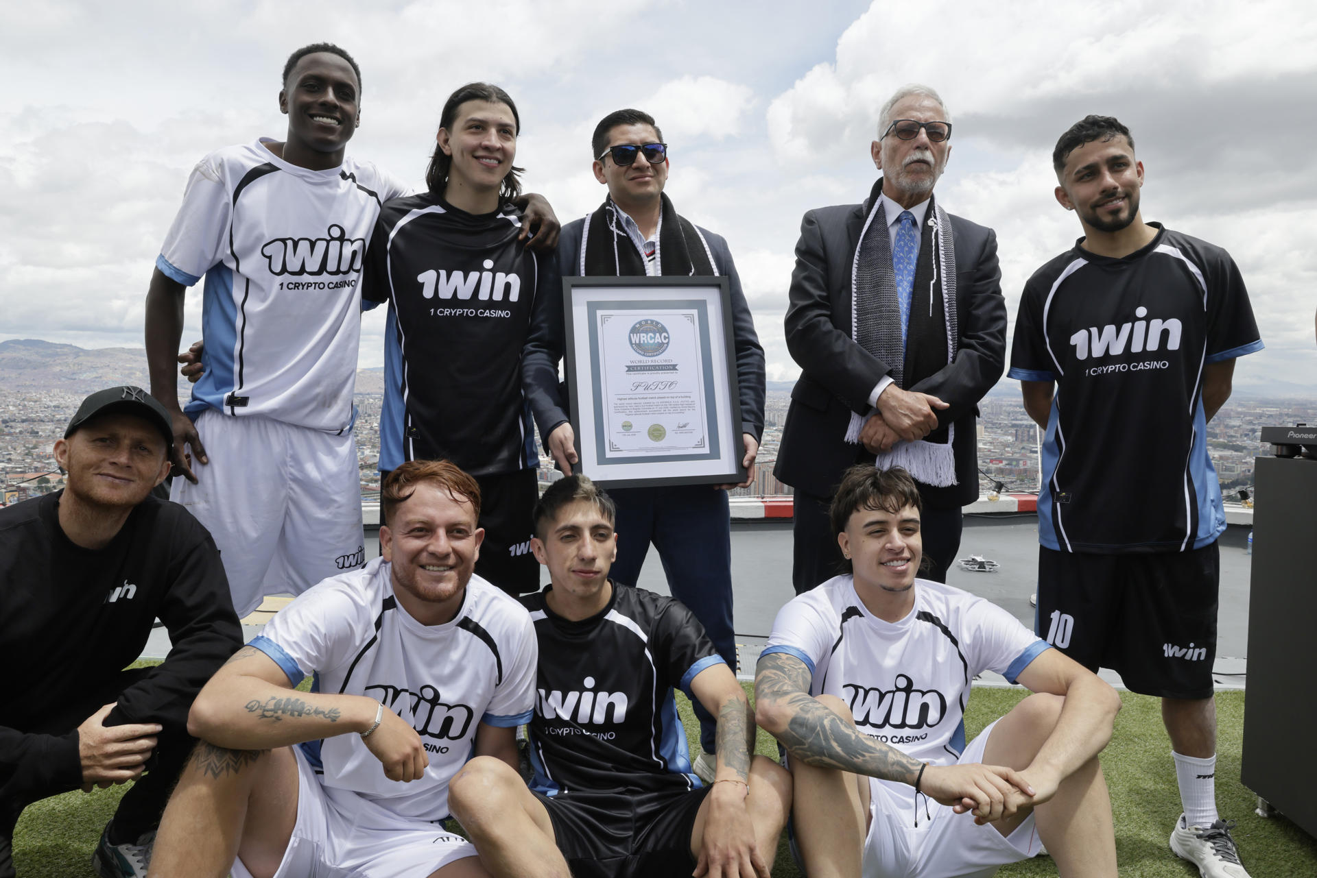 Integrantes de los equipos: la banda de Alex (blanco) y la bandera de Pablo (negro) posan con un certificado de la World Record Certification en el helipuerto de la Torre Colpatria en Bogotá (Colombia). Seis influenciadores y exponentes del fútbol callejero disputaron un partido a 196 metros de altura en la terraza superior de la Torre Colpatria, en Bogotá, en un evento presentado por sus organizadores como el encuentro de fútbol jugado a mayor altura de Latinoamérica. EFE/ Carlos Ortega
