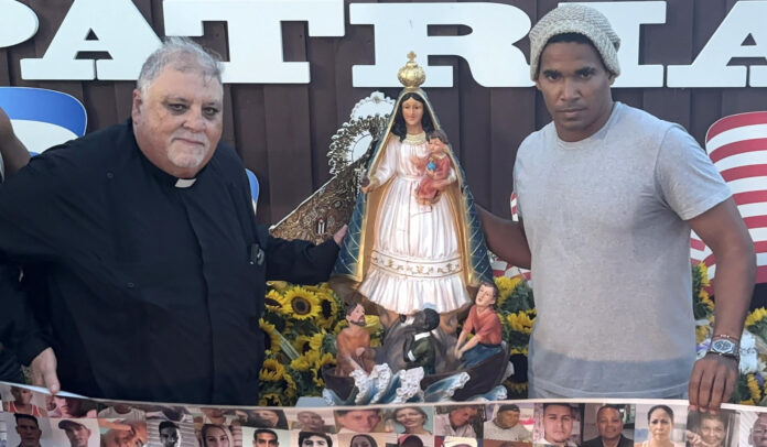 El artista plástico y opositor cubano Luis Manuel Otero Alcántara (d) y el padre Joaquín Espino visitan la 'Virgen de la Caridad del Cobre, durante un acto de reconstrucción este 18 de julio de 2026, en Miami. EFE/ Pablo Urbón
