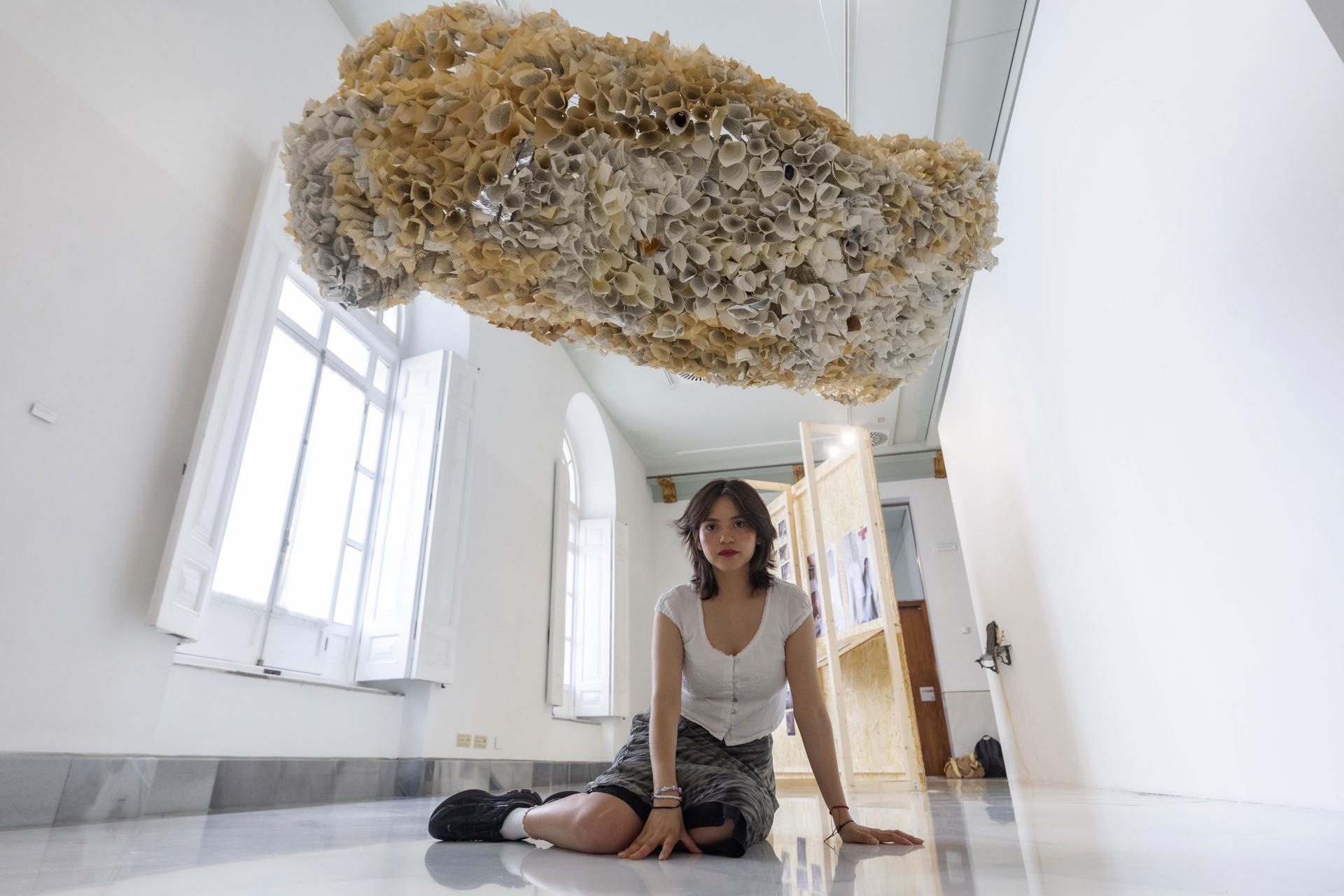 La artista ecuatoriana Nebraska Flores posa junto a su obra 'Escritura fósil', en la muestra titulada 'Los de aquí', en la que participan nueve artistas de Ecuador que hacen dialogar el arte contemporáneo con los movimientos migratorios, en Cartagena (España), con motivo del Festival Mar de Músicas, este año dedicado a Ecuador. EFE/Marcial Guillén
