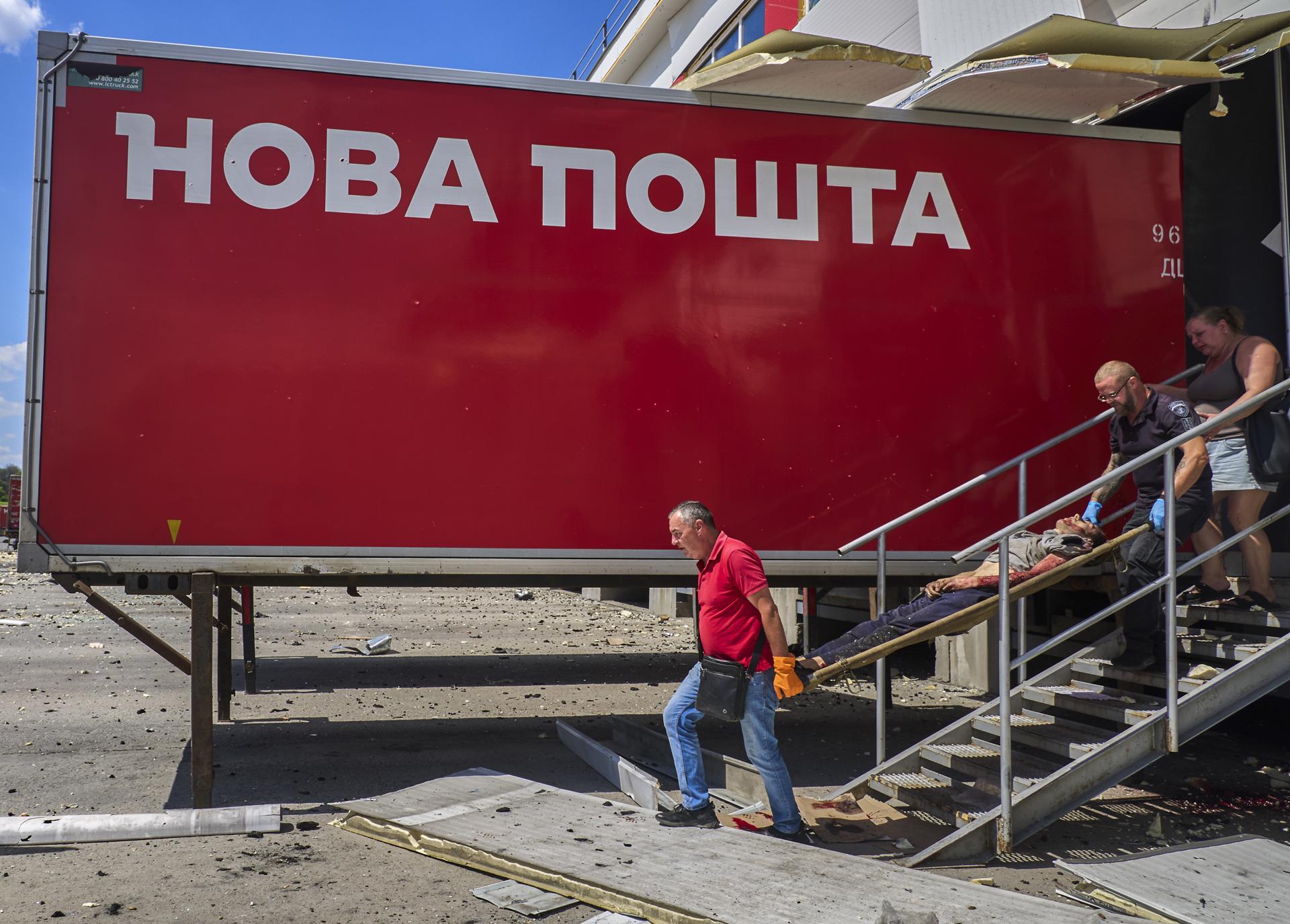 Járkov (Ucrania), 19/07/2026.- Un trabajador del servicio postal y un policía se llevan el cuerpo de uno de los muertos en el ataque ruso con misiles contra una terminal postal en un suburbio de la ciudad ucraniana de Járkov.
EFE/EPA/SERGEY KOZLOV ATTENTION: GRAPHIC CONTENT