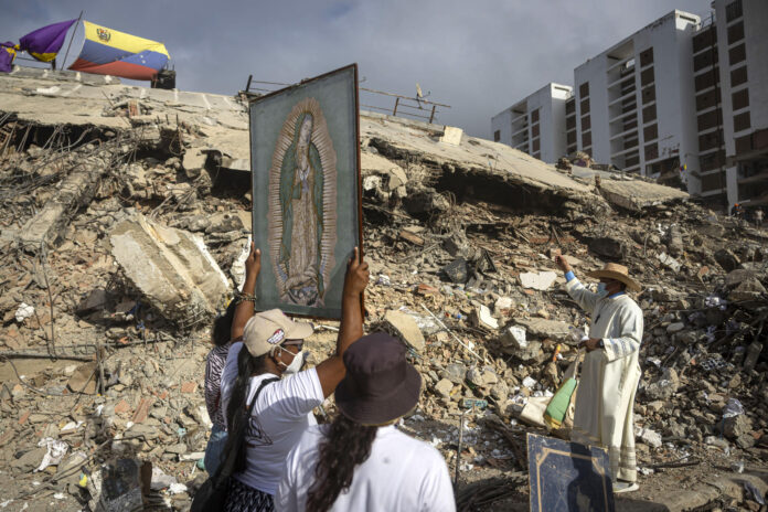 Fotografía de archivo que muestra personas junto al sacerdote Omar Pérez Gabino (d) durante un recorrido para acompañar con oraciones a familiares, voluntarios y rescatistas que continúan las labores de recuperación de cuerpos atrapados bajo los escombros tras los terremotos del pasado 24 de junio en Venezuela. EFE/ Miguel Gutiérrez
