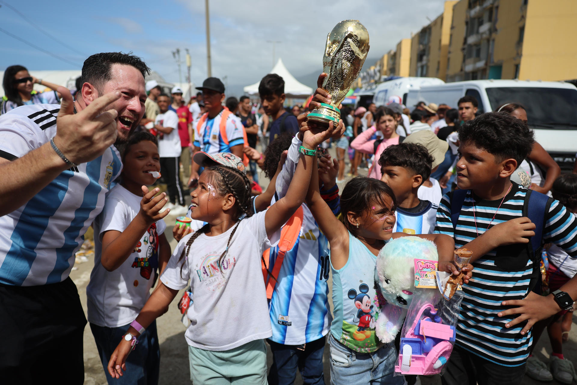 Niñas afectadas por los terremotos de Venezuela el 24 de junio sostienen una replica del trofeo del Mundial de la FIFA al momento que se juega la final entre España y Argentina en La Guaira (Venezuela). EFE/ Miguel Gutierrez