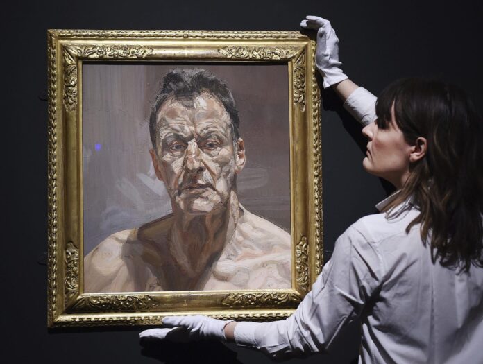 Una mujer sostiene la obra 'Reflejo' (autorretrato) de Lucian Freud en la casa de subastas Christie's de Londres, en junio de 2015. EFE/Andy Rain/Archivo.
