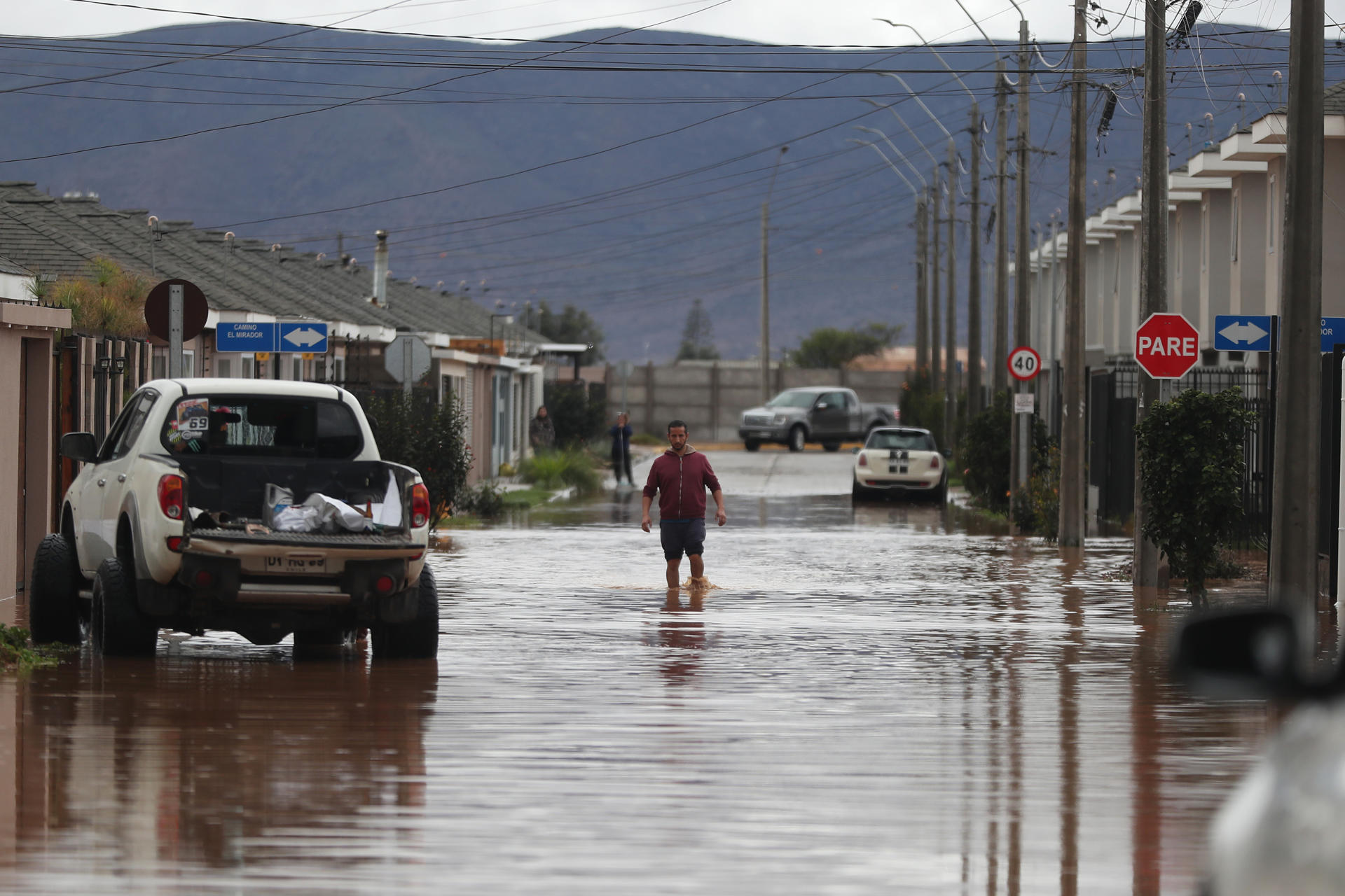 Una persona camina por una calle inundada por el desborde del Canal Bellavista, este lunes en el barrio Mirador de Hacienda, en La Serena (Chile). EFE/ Hernán Contreras