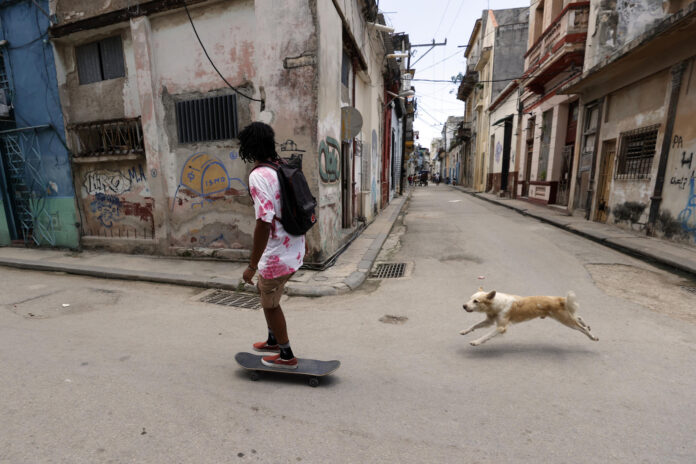 Fotografía del 9 de julio de 2026 de una persona en patineta junto a un perro en una calle de La Habana (Cuba). EFE/ Ernesto Mastrascusa
