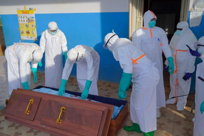 Imagen de archivo de personal médico con equipo de protección metiendo el cuerpo de una víctima de ébola en un ataúd en Bunia, en la RD del Congo. EFE/EPA/DIEUDONNE DIROLE
