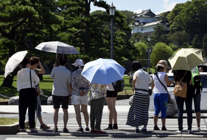 Varias personas se protegen del sol mientras pasean por los jardines del Palacio Imperial en Tokio, Japón, en una fotografía de archivo. EFE/FRANCK ROBICHON
