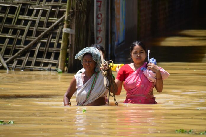 Una pareja de residentes camina por la zona inundada tras las fuertes lluvias en Teok, en el distrito de Jorhat, estado de Assam, la India. EFE/EPA/ANUWAR ALI HAZARIKA
