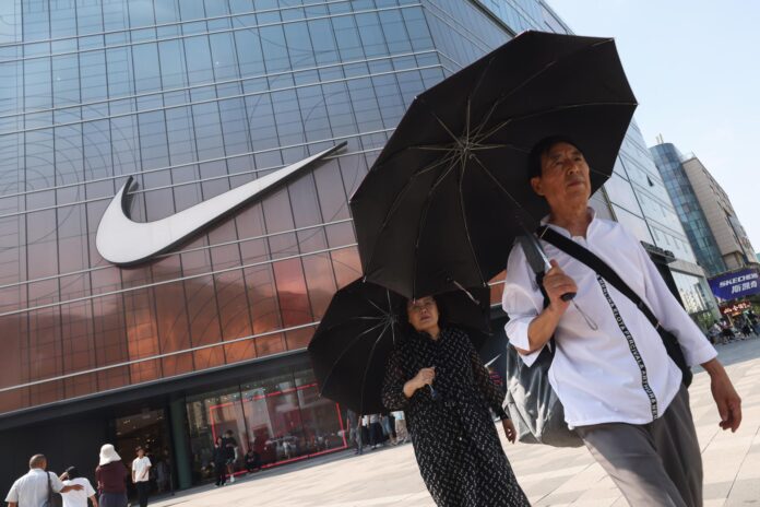 Imagen de archivo de varias personas cerca de una tienda Nike en Pekín, China, el 11 de agosto de 2025. 
EFE/EPA/WU HAO
