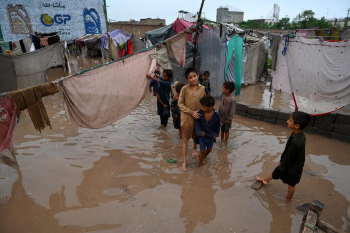 Niños juegan en una zona inundada tras las fuertes lluvias del monzón en Peshawar, Pakistán. EFE/EPA/BILAWAL ARBAB
