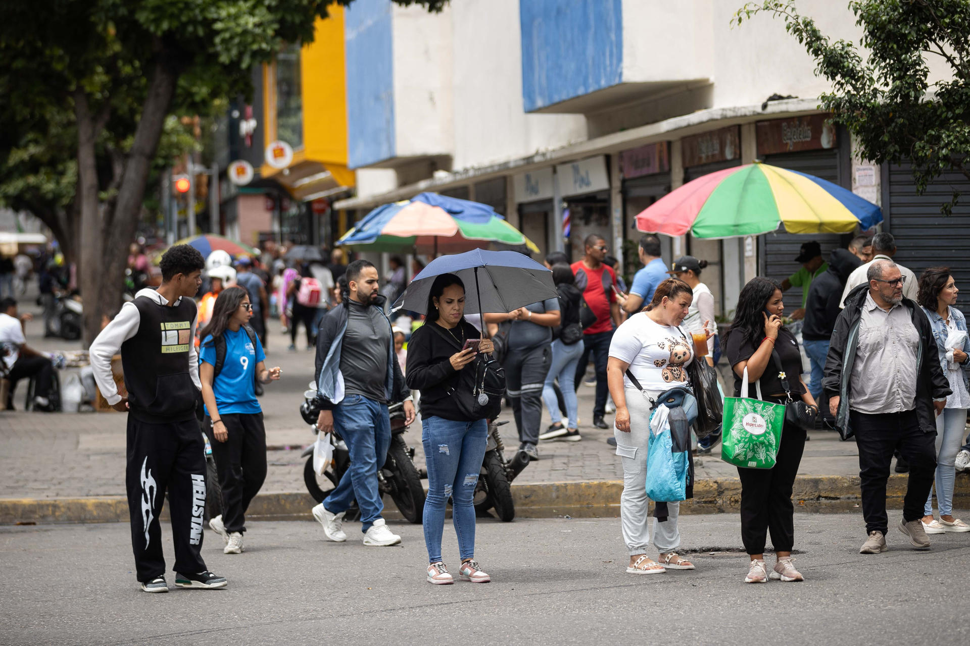 Personas se protegen de la lluvia este lunes, en Caracas (Venezuela). EFE/ Ronald Peña R