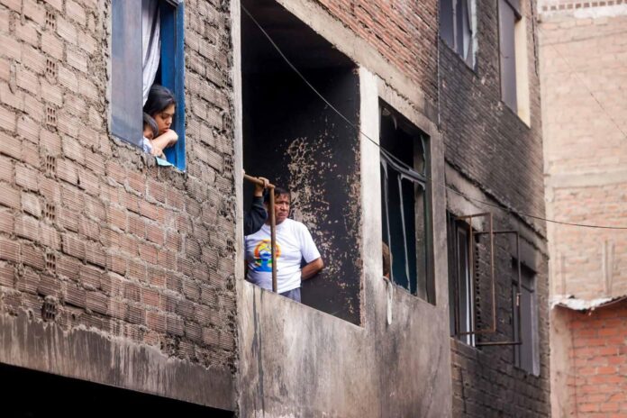 Fotografía cedida por la Agencia Andina que muestra a integrantes de la Policía de Perú custodiando varias viviendas tras un incendio en Lima (Perú). EFE/ Luis Iparraguirre
