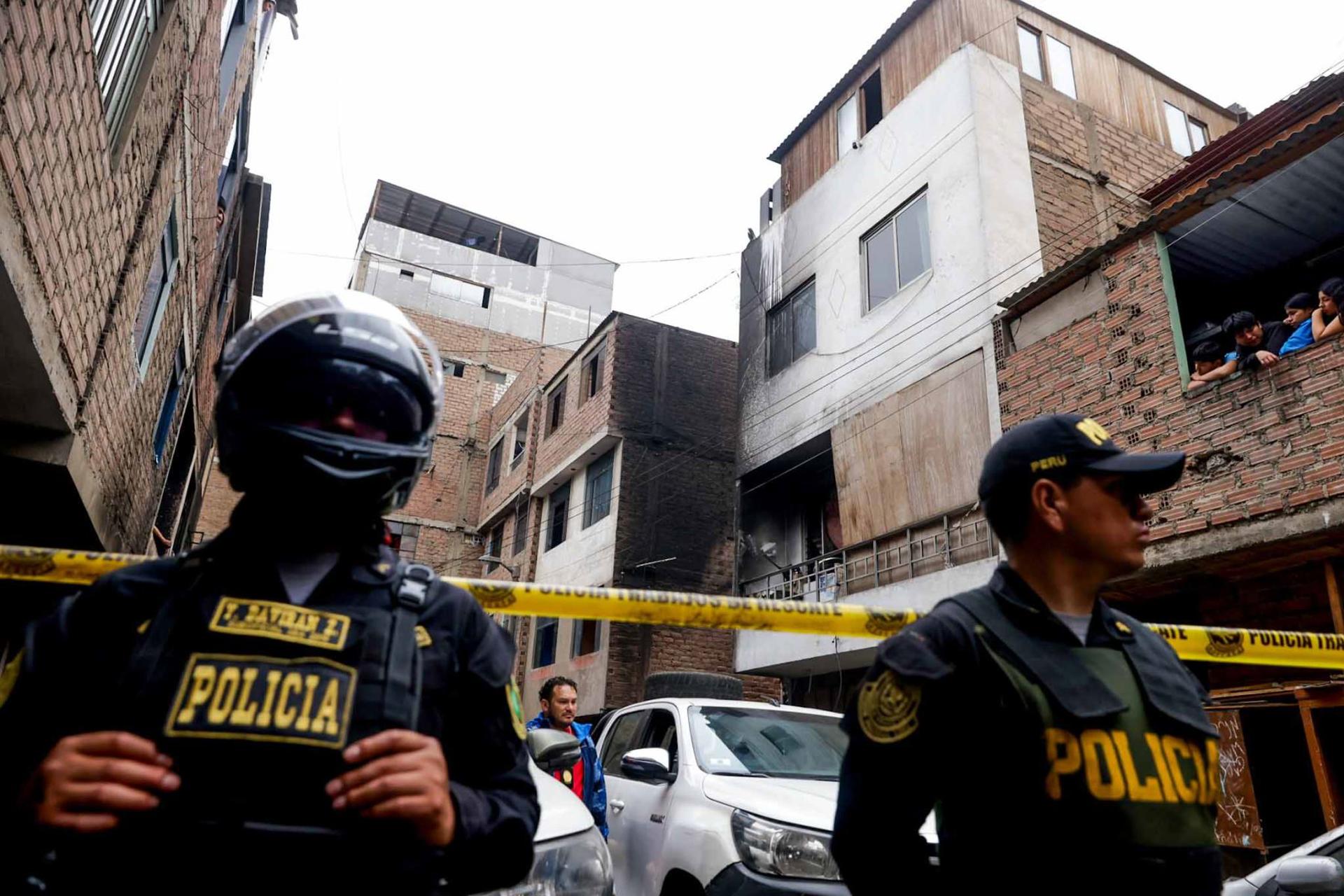Fotografía cedida por la Agencia Andina que muestra a integrantes de la Policía de Perú custodiando varias viviendas tras un incendio en Lima (Perú). EFE/ Luis Iparraguirre