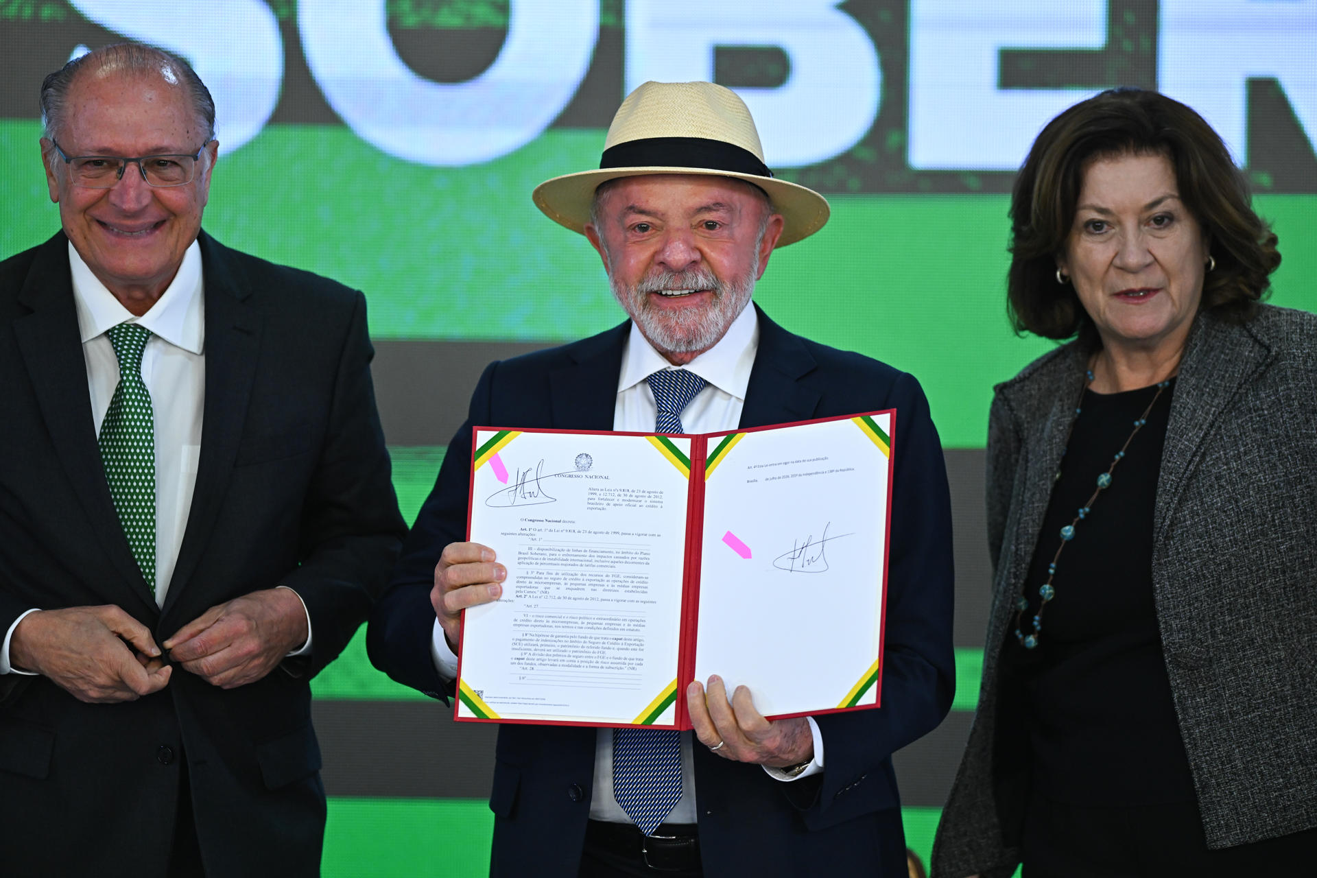 El presidente de Brasil, Luiz Inácio Lula da Silva (c), sostiene un documento junto al vicepresidente, Geraldo Alckmin (i), y de la jefa de Gabinete de la Presidencia, Miriam Belchior, durante la ceremonia de sanción del Proyecto de Ley de Conversión, que asigna recursos a las líneas de crédito del programa 'Brasil Soberano' en apoyo de las empresas afectadas por los aranceles comerciales de Estados Unidos, este miércoles en el Palacio del Planalto, en Brasilia (Brasil). EFE/ Andre Borges
