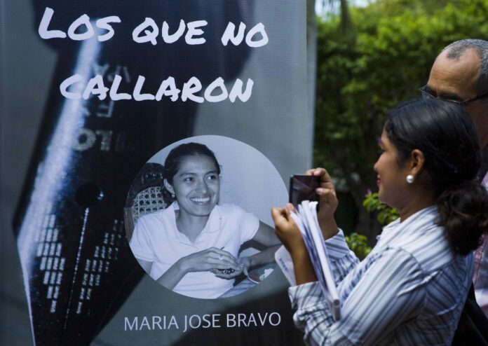 Fotografía de archivo en la que se captó a una joven al tomar una instantánea de una pancarta con el rostro de una periodista asesinada en Nicaragua. EFE/Jorge Torres
