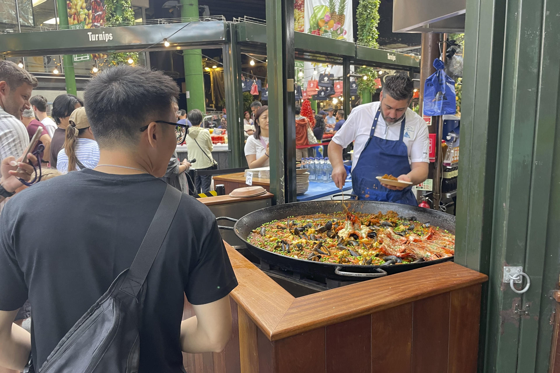 El mercado gastronómico de Borough, uno de los más populares de Londres, recibe a diario largas colas de visitantes para comprar una porción de paella en el puesto de arroces que causa furor entre los turistas y visitantes y donde se venden más de 1.000 raciones a diario. Son las diez de la mañana y huele a aceite de oliva, ajo, cebolla, pimiento y tomate rallado, el tradicional sofrito de paella. También se escucha cómo las cucharas rascan el fondo de la paellera para obtener el característico 'socarrat'. Esta escena podría ser la típica imagen, salvando la hora, en cualquier restaurante, bar o calle del Mediterráneo español. Sin embargo, el lugar es el mercado gastronómico de Borough en Londres.-EFE/ Luis Campello