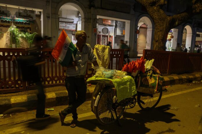 Un hombre fue captado este 23 de julio al vender banderas de India mientras seguidores del Partido Cockroach Janta de la India (CJP) mantienen sus protestas, en Nueva Delhi (India). EFE/Rajat Gupta

