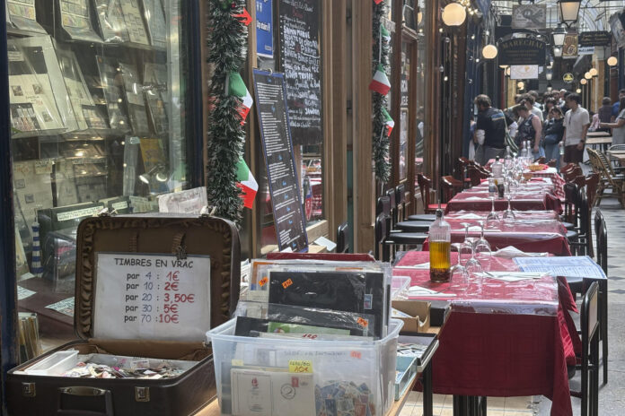 Venta de sellos frente a las mesas de un restaurante italiano junto a una aglomeración de turistas al fondo.-EFE/ Pol Lloberas
