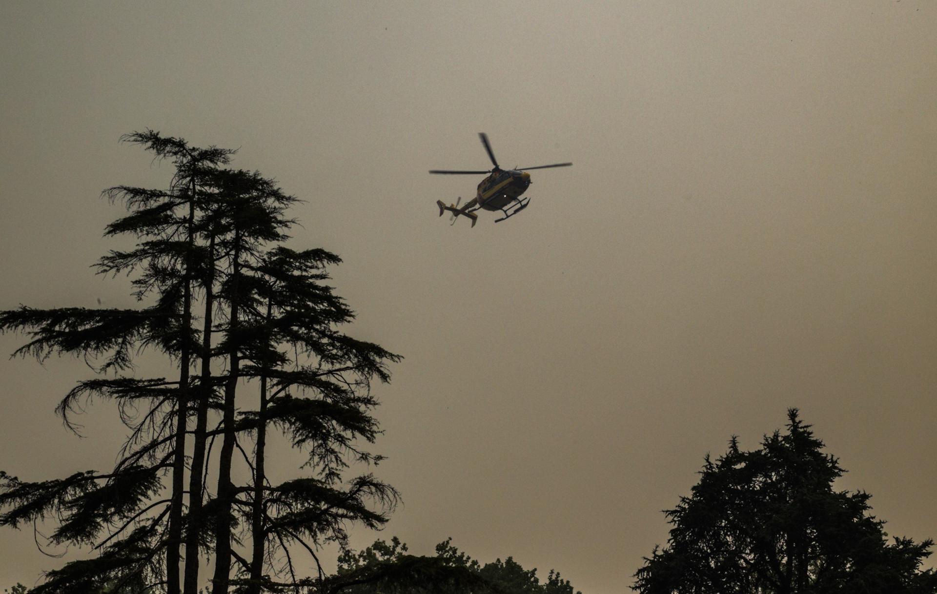 Un helicóptero de extinción de incendios vuela entre el humo de un incendio forestal que se propaga en Cap Ferret, en Lège-Cap-Ferret, en el suroeste de Francia. EFE/EPA/JULIEN REGUL
